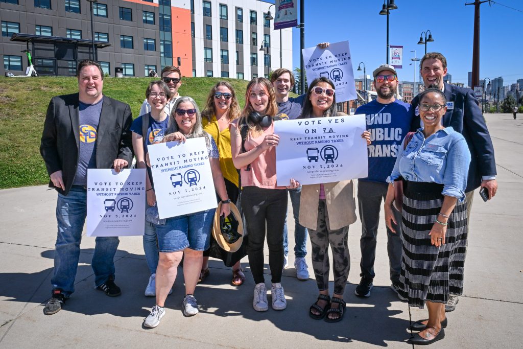 A group of people are smiling and holding yes on 7A signs