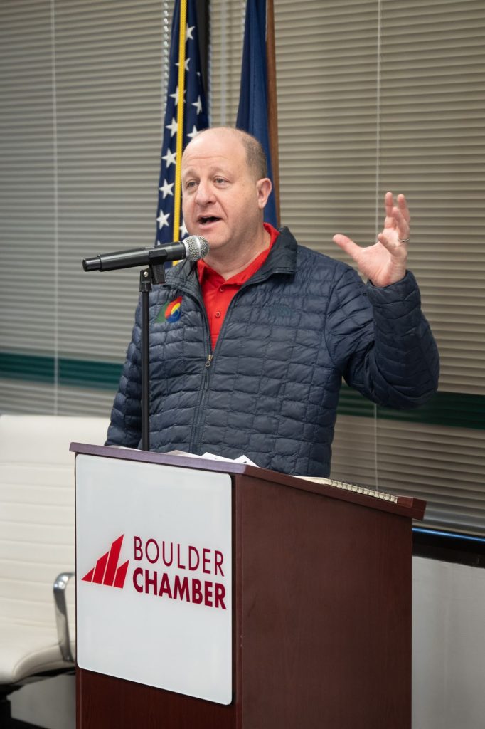 Governor Jared Polis speaks at the podium at the Boulder Chamber