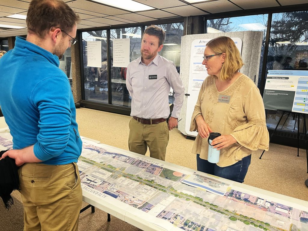 Three people stand around a long, printed map.